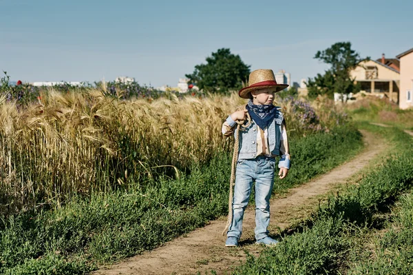 Little boy dressed in Western style in the field , retro style