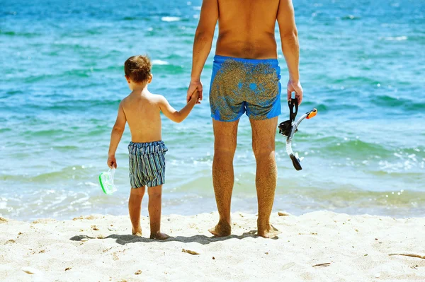 Father and son on the beach with underwater equipment . Father teaches son how to swim