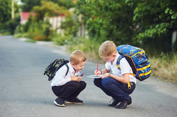 Two elementary school students with books. Behind the boy\'s school backpack.