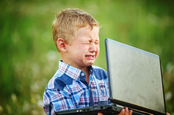 Little boy crying bitterly, holding the laptop