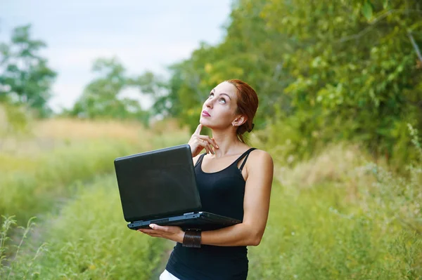 A young emotional girl with laptop in the Park