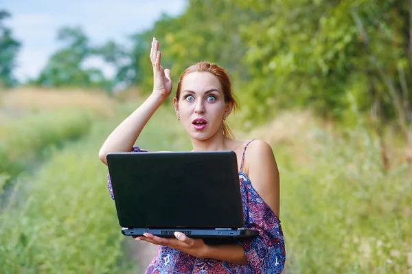 A young emotional girl with laptop in the Park