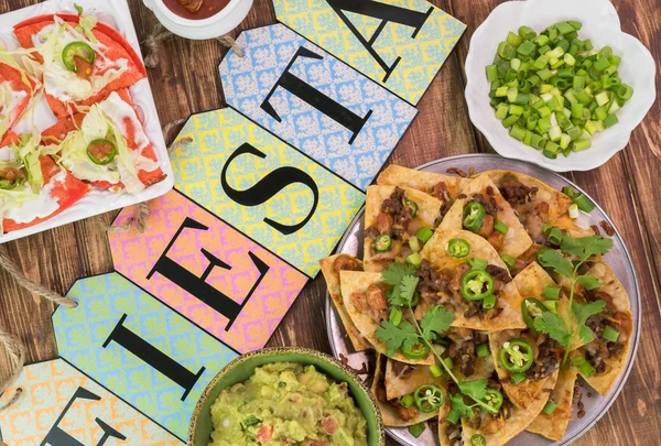 Mexican fiesta table with nachos, tortilla chips, quesadillas, guacamole dip.