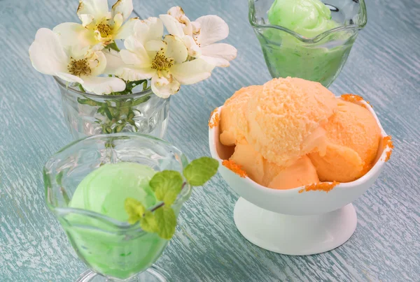 Lime and orange sherbet in ice cream bowls.