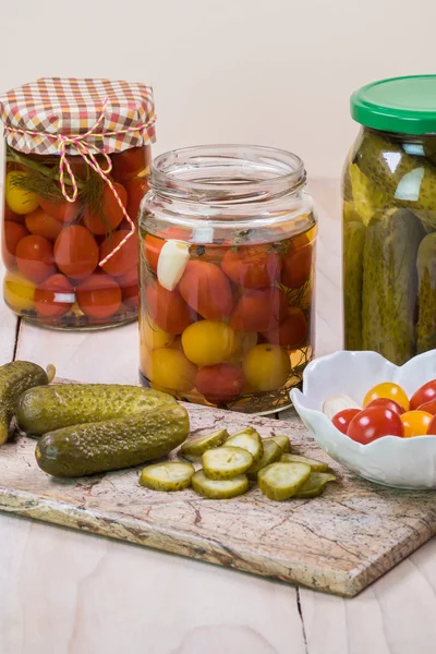 Assorted vegetable pickles in glass jars and  pickles on a cutti