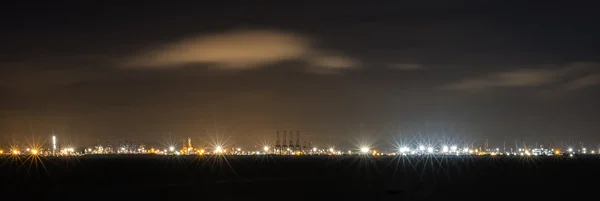 Panorama far view of with flare stack of cargo ship and crane at port at night in Thailand