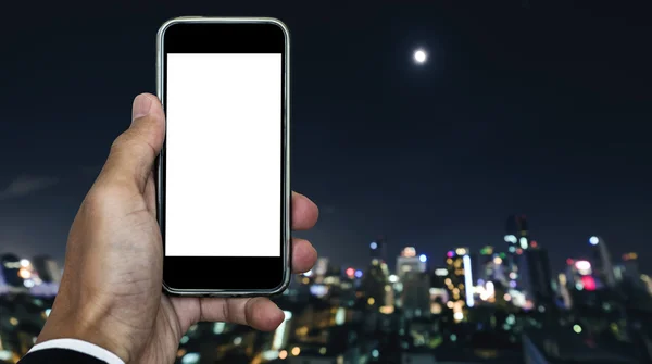 Businessman holding mobile phone with copy space on screen, and defocus nightlife city view