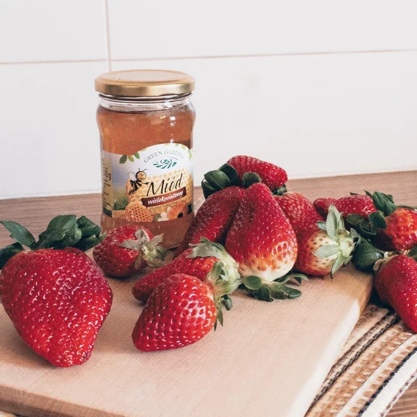 Ripe strawberries and jar of honey