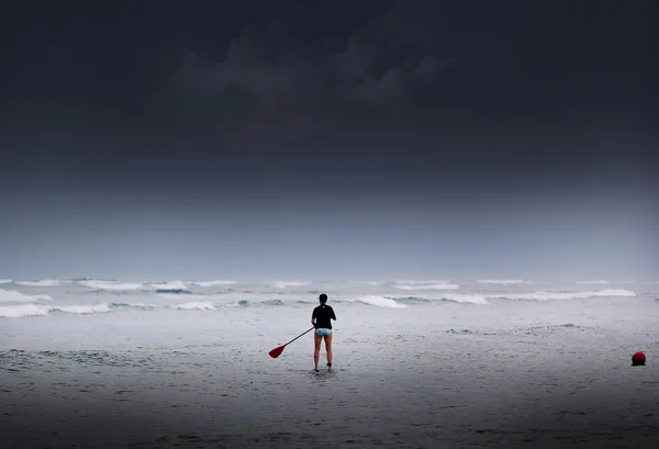 Silhouettes of Stand up paddle surfer at overcast sea