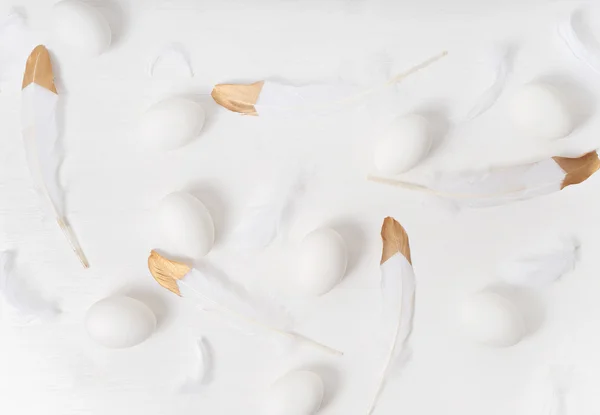White eggs on white background with feathers