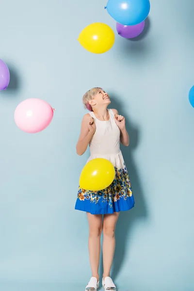 Girl have fun with colored balloons on blue background