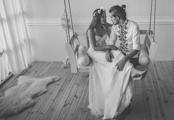 Young and beautiful bride and groom are having a good fun time and happy together while shooting a wedding photosession in studio with rustic decorations and wooden backgrounds