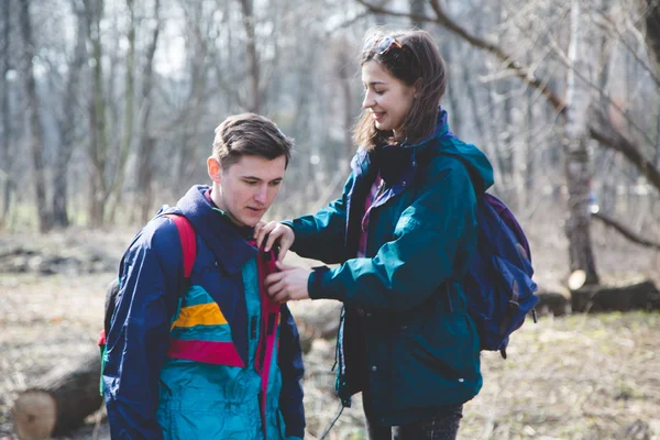 Young beautiful happy hipster couple brunette girl and guy having great fun time while travelling and walking in the woods forest