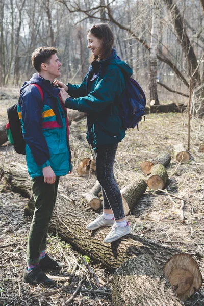 Young beautiful happy hipster couple brunette girl and guy having great fun time while travelling and walking in the woods forest
