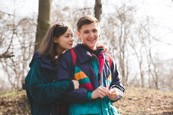 Young beautiful happy hipster couple brunette girl and guy having great fun time while travelling and walking in the woods forest