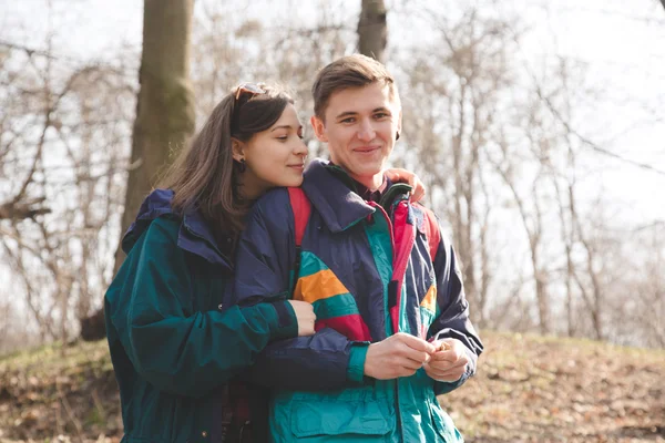 Young beautiful happy hipster couple brunette girl and guy having great fun time while travelling and walking in the woods forest