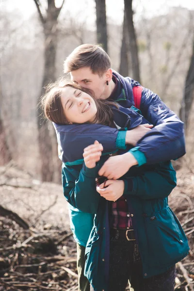 Young beautiful happy hipster couple brunette girl and guy having great fun time while travelling and walking in the woods forest