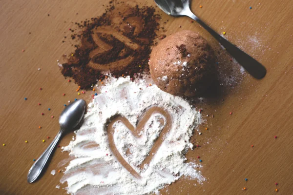 Cookie homemade preparation recipe step ingredients on wooden table flour, cocoa powder, dough pastry with cute heart shapes
