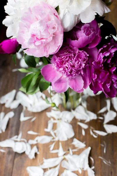 White and pink peonies bouquet from flowers market on a dark wood table in rustic style