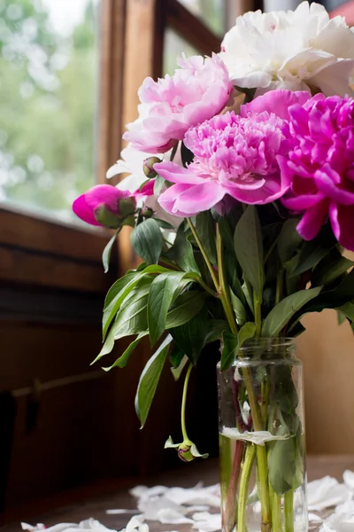 White and pink peonies bouquet from flowers market on a dark wood table in rustic style