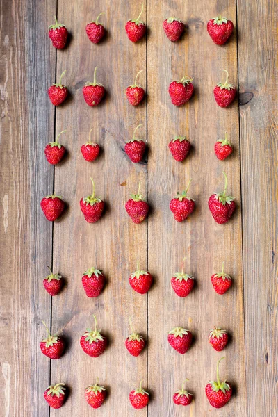Organic fresh sweet strawberries in rows as a seasonal breakfast in the morning right from farmers market on dark wood table background decorated in rustic style