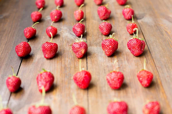 Organic fresh sweet strawberries in rows as a seasonal breakfast in the morning right from farmers market on dark wood table background decorated in rustic style
