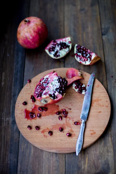 Organic pomegranate open cut in half and full one on a wooden dark table background decorated in rustic style