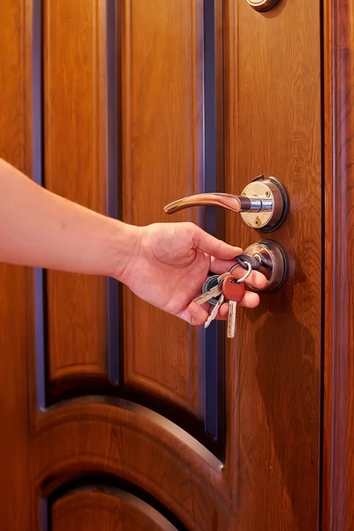 Hands inserting keys in door lock