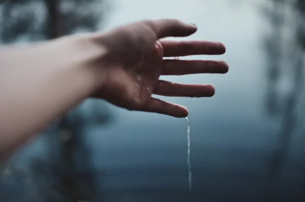 Water flows down from Human hand on grey background