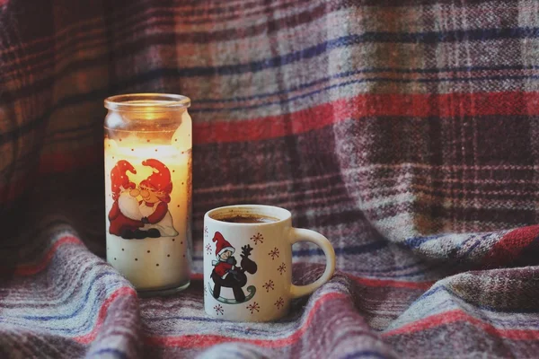 Cup of coffee and Christmas candle on checkered plaid