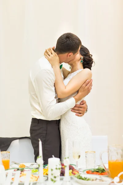 Romantic happy handsome groom kissing beautiful white dress bride at wedding reception