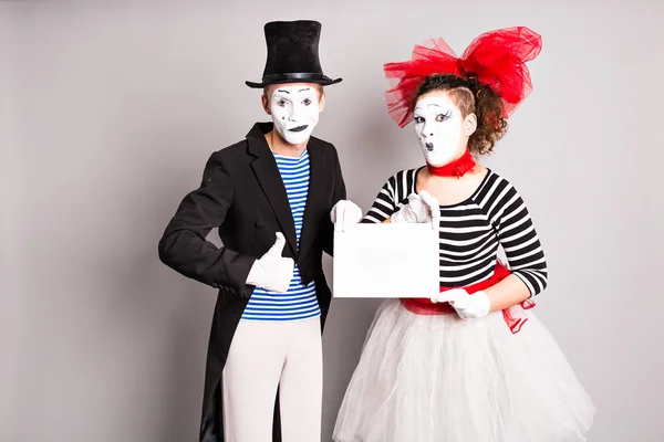 Your text here. Actors mimes holding empty blank board. Colorful studio portrait with gray background. April fools day