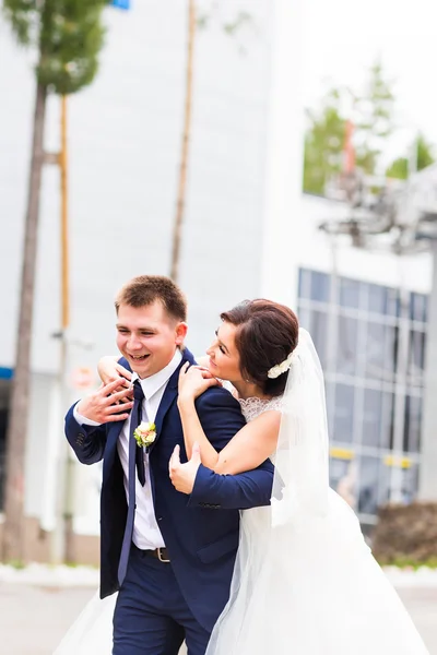 Portrait of happy laughing bride and groom on street at sunny day