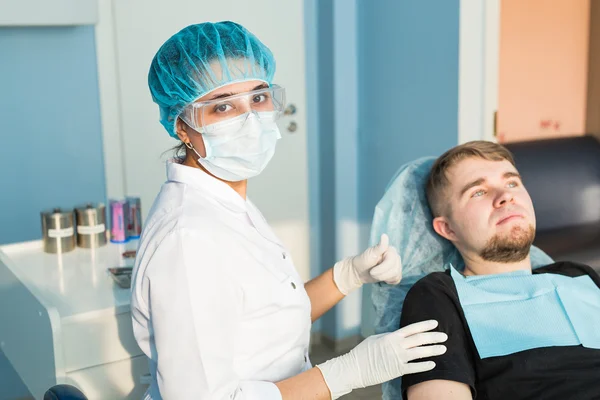 People, medicine, stomatology and healthcare concept - happy young female dentist with tools over medical office background