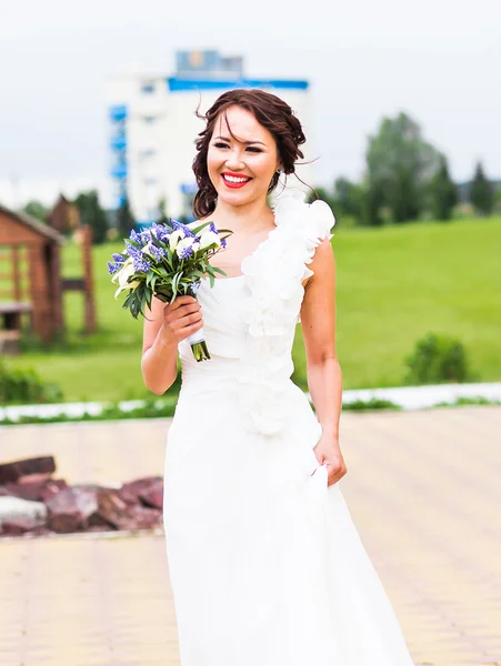 Bride holding bouquet of white calla lilies and blue flowers