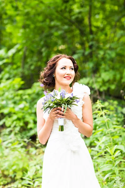 Bride holding bouquet of white calla lilies and blue flowers