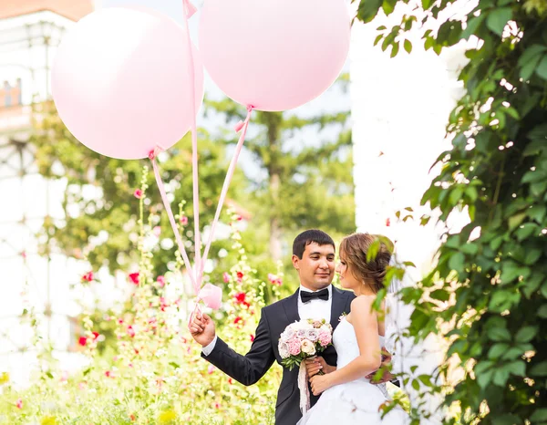 Summer holidays, celebration and wedding concept - couple with colorful balloons