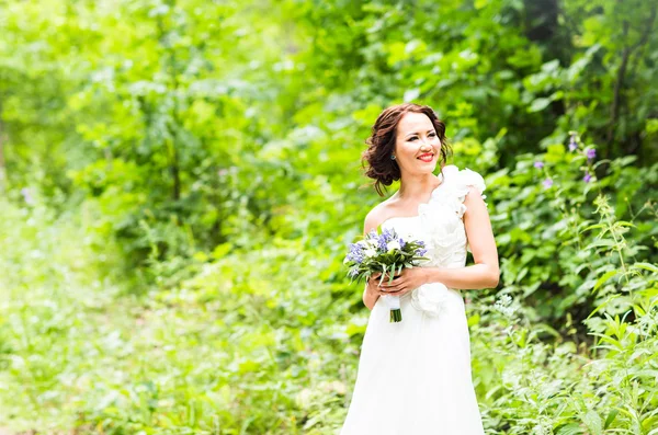 Bride holding bouquet of white calla lilies and blue flowers