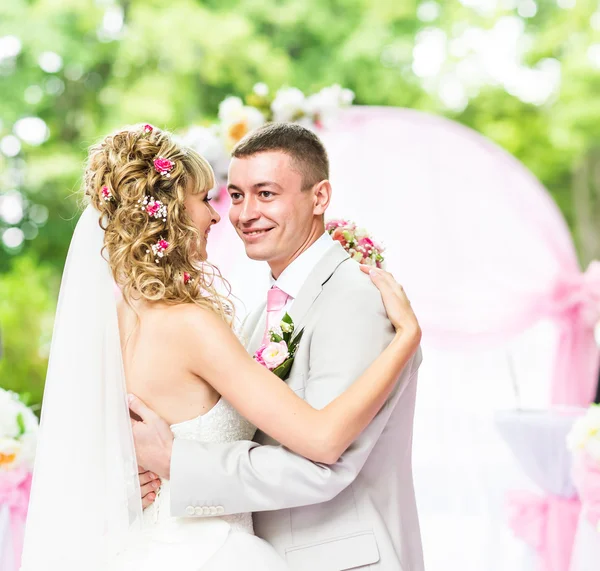 Happy newlywed romantic couple dancing at wedding aisle with pink decorations and flowers