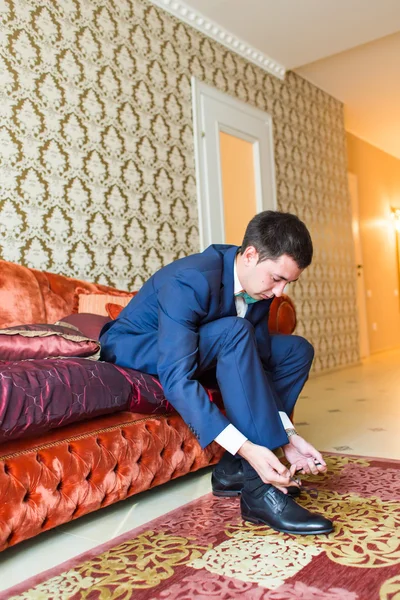 Groom is wearing shoes indoors. Male portrait of handsome guy. Beautiful model boy in colorful wedding clothes.