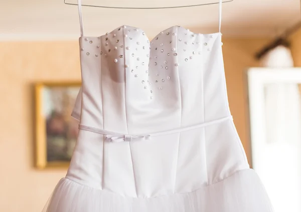 The perfect wedding dress on a hanger in the room of bride