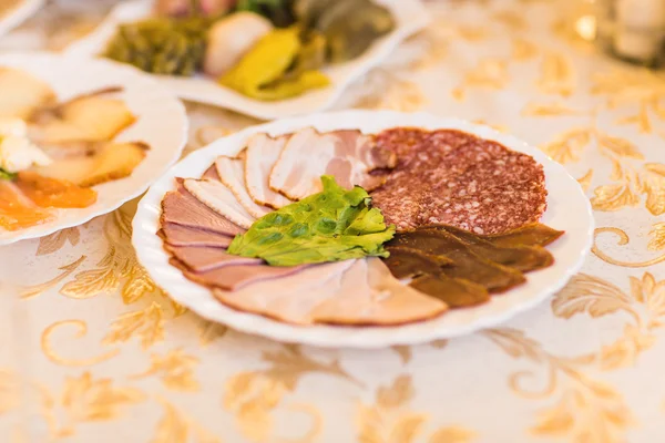 Platter of sliced ham,salami and cured meat with vegetable decoration on festive table