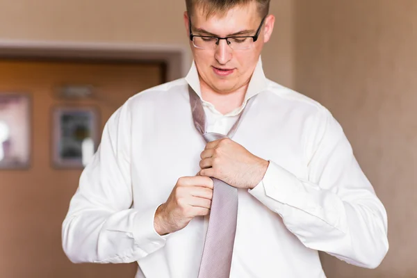 Man in a suit fixing his tie.