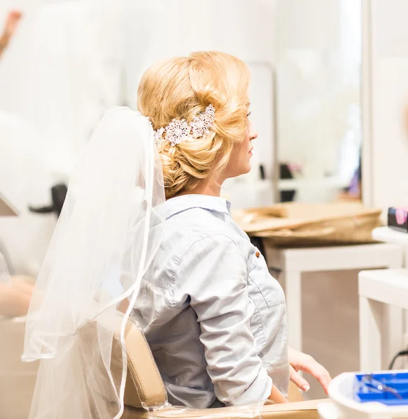 Hair stylist makes the bride before a wedding