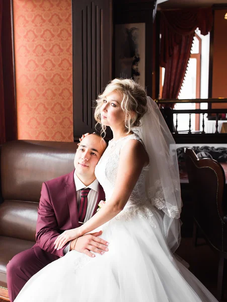 Bride and groom sitting  in a luxurious chair. Loving couple together indoors.