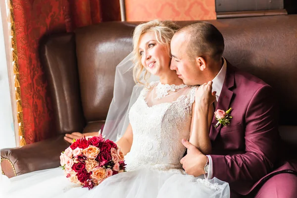 Bride and groom sitting  in a luxurious chair. Loving couple together indoors.