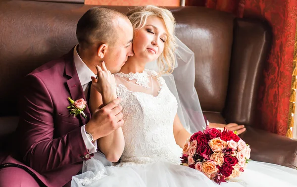 Bride and groom sitting  in a luxurious chair. Loving couple together indoors.