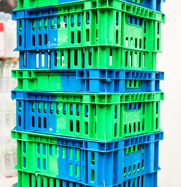 Pile of Plastic Pallets Blue And Gray Color Stacked Beside A Store.