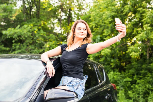 Woman taking smartphone selfie photo on car summer travel vacation.