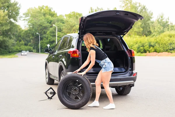 Woman changing tire on a road